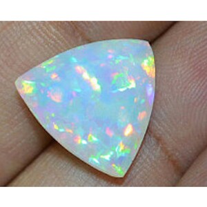 May include: A triangular white opal gemstone with iridescent rainbow flashes.