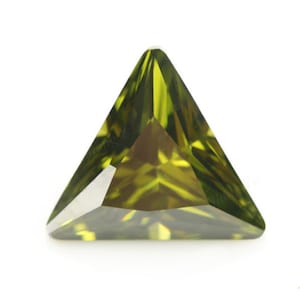May include: A triangular green gemstone with a faceted cut.