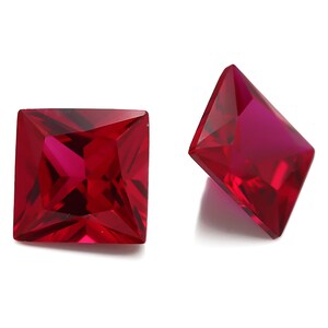 May include: Two red square-shaped gemstones with a faceted cut.