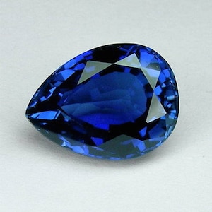 May include: A deep blue pear-shaped sapphire gemstone with a faceted cut.