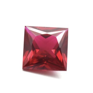 May include: A square-shaped, faceted, red gemstone with a brilliant cut.