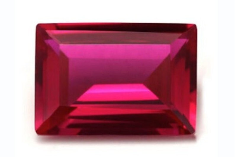 May include: A deep red rectangular gemstone with a faceted cut.