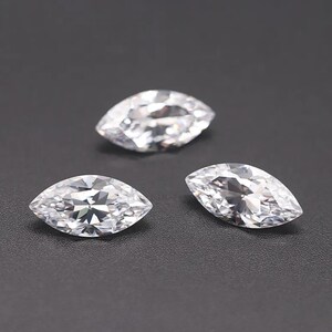 May include: Three clear marquise-shaped gemstones on a black background.