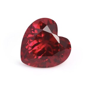 May include: A deep red heart-shaped gemstone with a faceted cut.