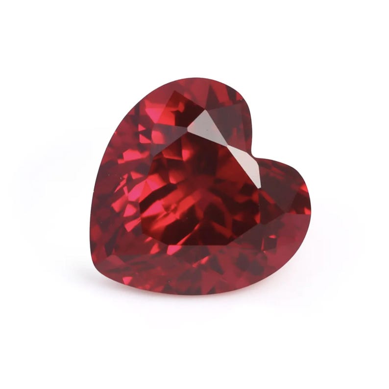 May include: A deep red heart-shaped gemstone with a faceted cut.