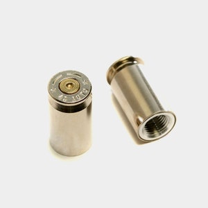 May include: Two silver bullet-shaped bottle stoppers. The stoppers have a threaded opening on one end and a flat top with the text "45 AUTO" on the other end.