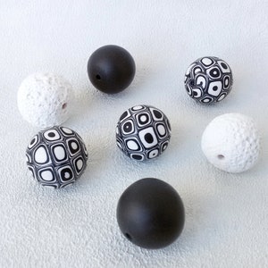 May include: A set of seven round beads, some with a black and white geometric pattern, some with a textured white surface, and some solid black.