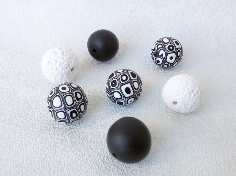 May include: A set of seven round beads, some with a black and white geometric pattern, some with a textured white surface, and some solid black.