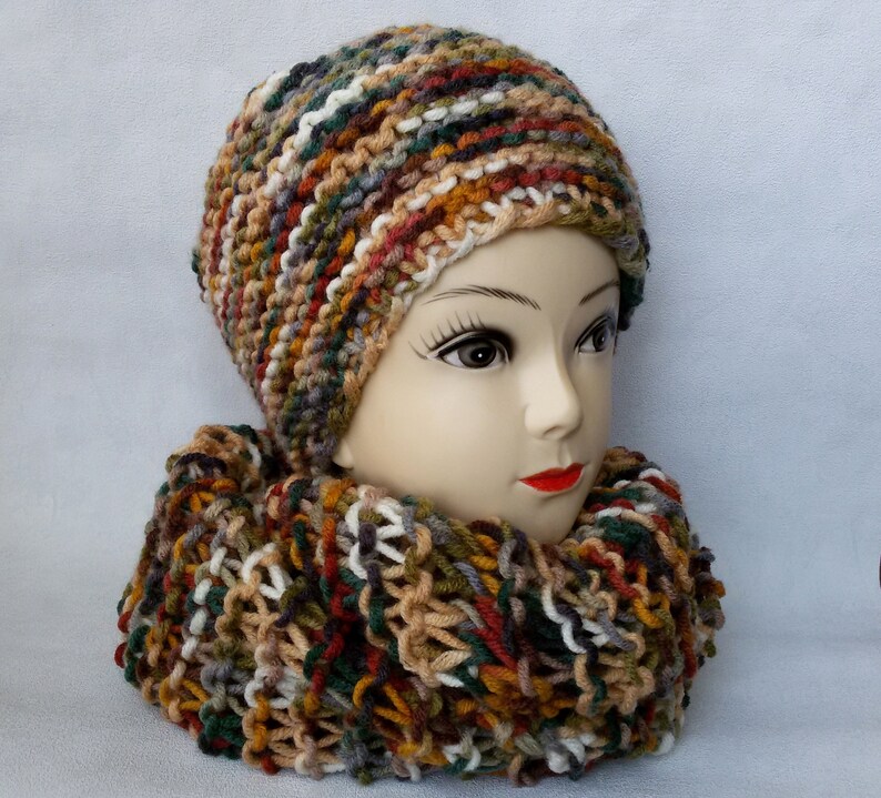 May include: A knitted hat and scarf set in a multi-colored pattern of brown, green, white, and orange.