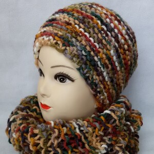 May include: A multi-colored knitted hat and matching scarf in shades of brown, green, white, and red.