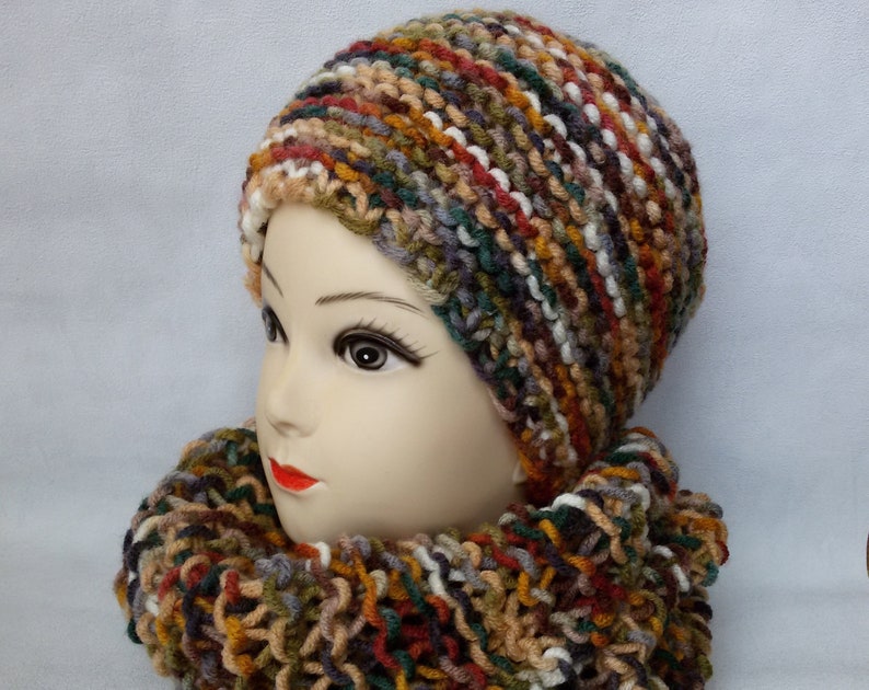 May include: A multi-colored knitted hat and matching scarf in shades of brown, green, white, and red.