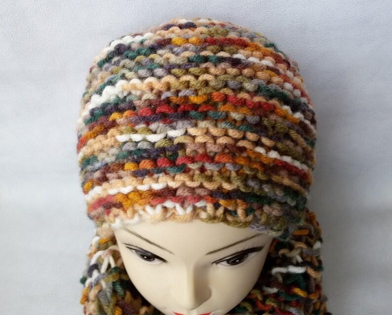 May include: A multi-colored knitted hat and scarf set with a mix of brown, orange, green, white, and gray yarn.