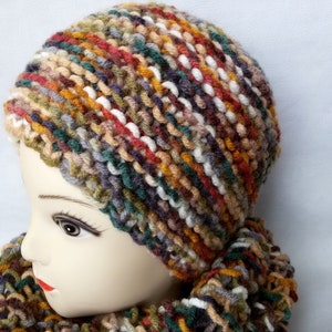 May include: A colorful knitted hat and matching scarf in shades of brown, green, white, and red. The hat is a slouchy beanie style and the scarf is a long, thin style.