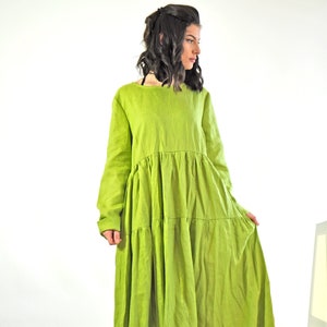 May include: A long, tiered, green linen dress with long sleeves. The dress is loose-fitting and has a relaxed silhouette.