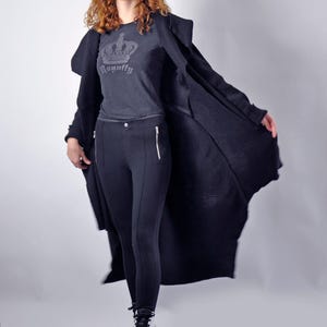 A model walking forward with the black long cardigan open and billowing outward.