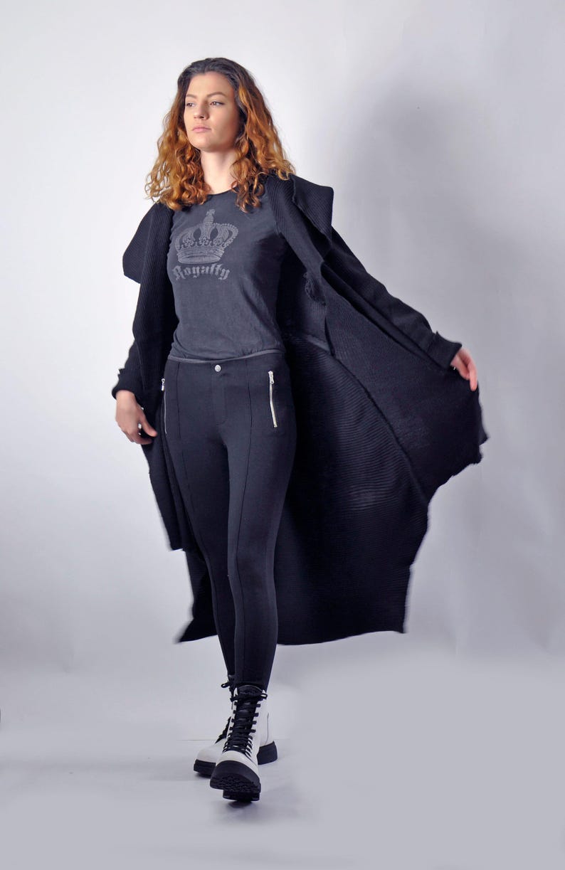 A model walking forward with the black long cardigan open and billowing outward.