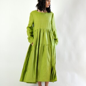 May include: A long, tiered, lime green linen dress with long sleeves and a round neckline. The dress is flowy and has a relaxed fit.