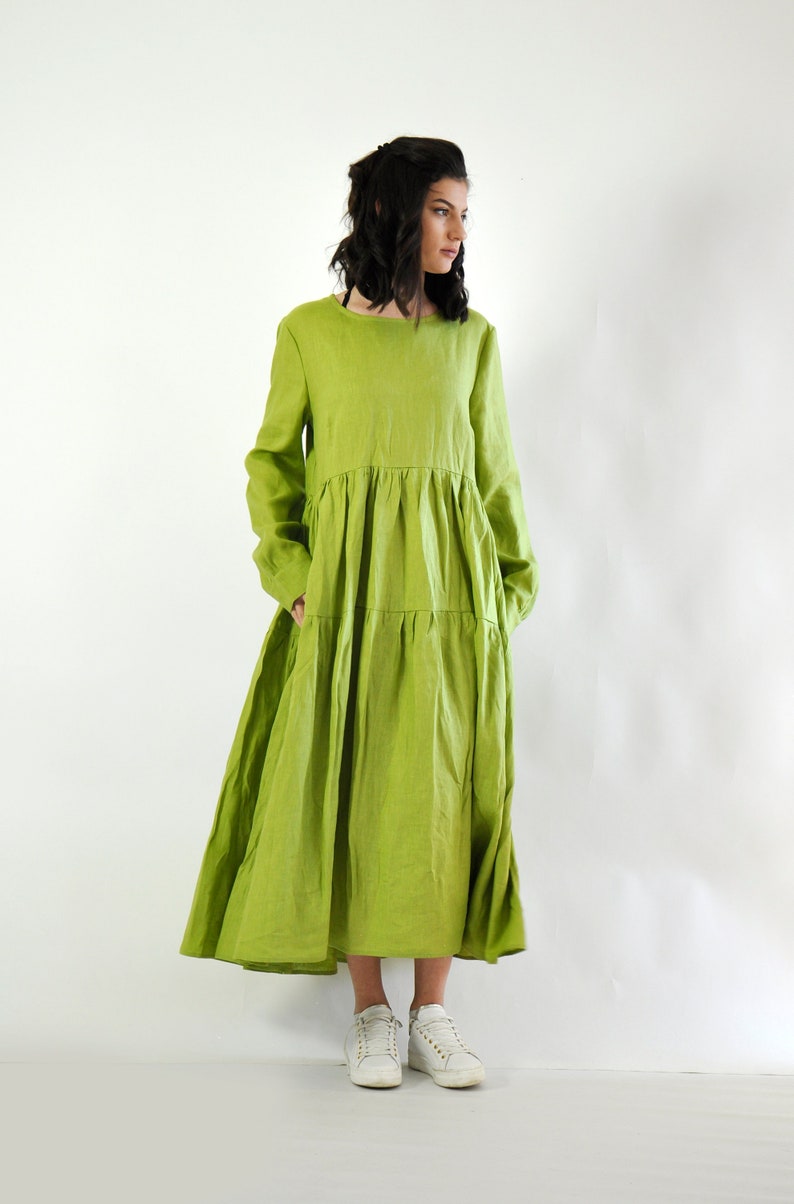 May include: A long, tiered, lime green linen dress with long sleeves and a round neckline. The dress is flowy and has a relaxed fit.