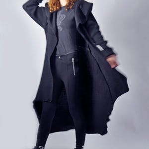 A dynamic shot of a model posing with the long black cardigan flared out around her.