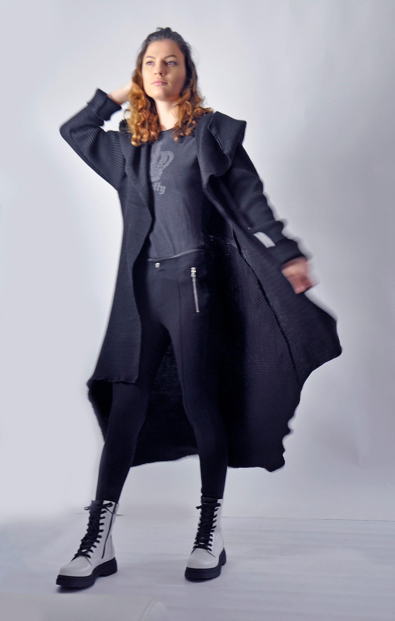 A dynamic shot of a model posing with the long black cardigan flared out around her.
