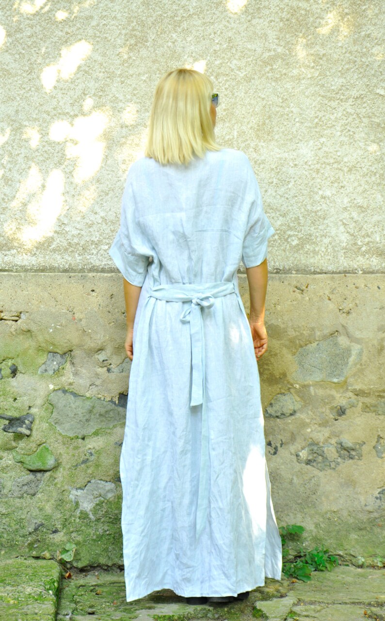 Puede incluir: Un vestido de lino azul claro con cintur&oacute;n de lazo. El vestido tiene un corte holgado y una falda larga y fluida.