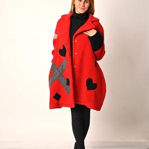 May include: A red fleece coat with black heart and grey geometric designs. The coat has a button closure and a collar.