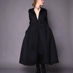 May include: A black long-sleeved coat with a V-neckline and a belt. The coat has a flared skirt and is worn with black boots.