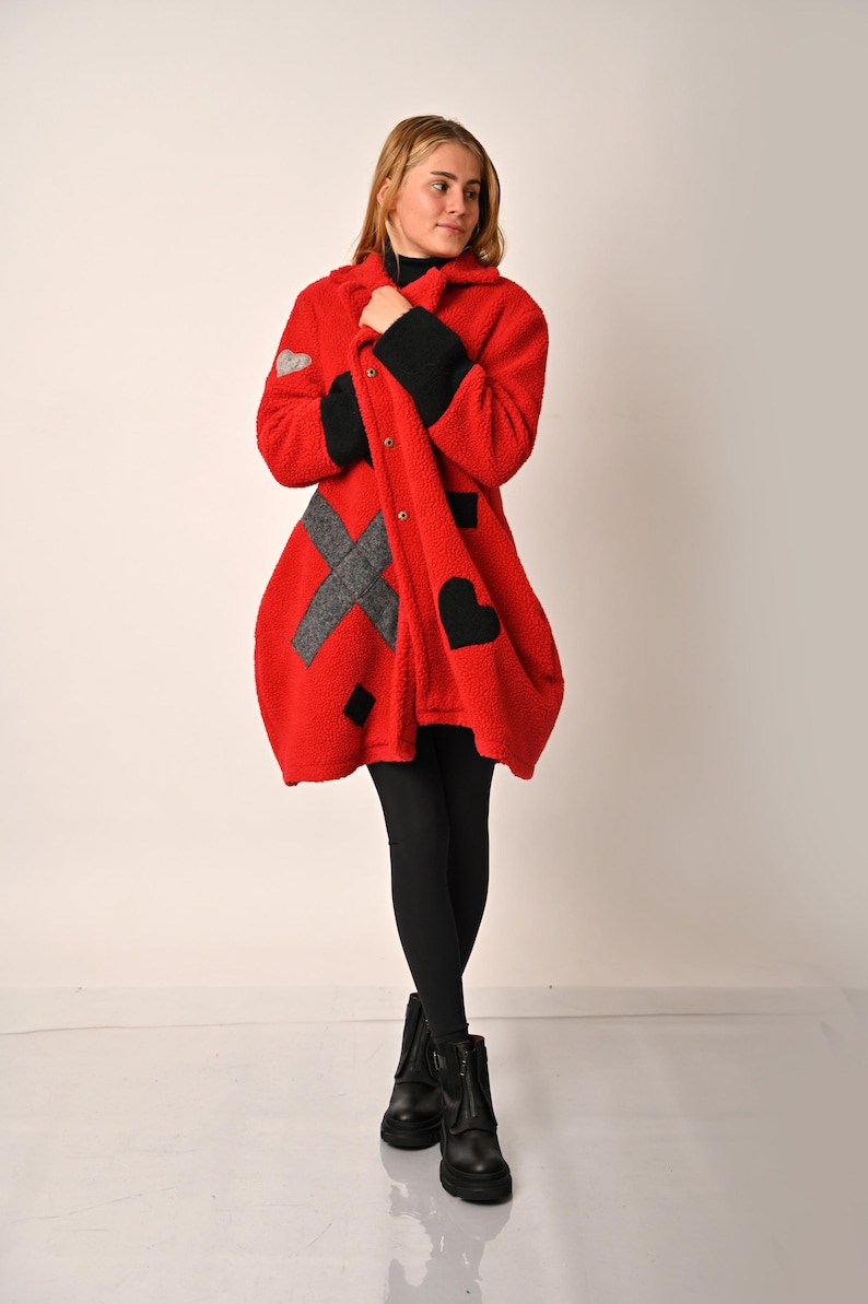 May include: A red fleece coat with black and grey geometric designs. The coat has a button closure and a collar.
