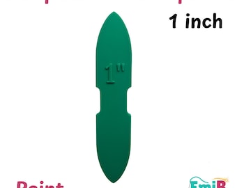 May include: A green strap anchor template with a pointed top and bottom, featuring the text 1 inch at the top and 1" embossed on the center. The image includes the text Strap Anchor Templates, 1 inch, and Point, with an EmiB Designs logo.