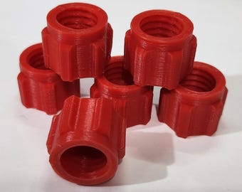 May include: A collection of six red, cylindrical components with a threaded interior and ridged exterior. The components are stacked and arranged on a white surface. The objects appear to be made of plastic.