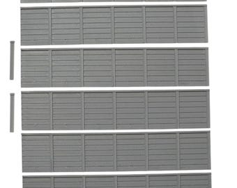 May include: Six rectangular gray fence panels arranged in horizontal rows, each featuring a series of vertical slats and a top rail. To the left of the panels are two thin, vertical gray posts with flat caps, designed for assembly with the fencing.