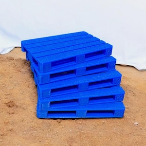Könnte beinhalten: Ein Stapel aus fünf blauen Plastikpaletten. Die Paletten sind übereinander gestapelt, wobei die oberste Palette leicht versetzt ist.
