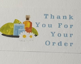 Puede incluir: Una pegatina azul y blanca con el texto "Thank You For Your Order". La pegatina presenta una ilustración de dos velas azules, una botella de aceite y flores blancas.