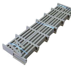 Puede incluir: Una pila de rejillas rectangulares de color gris claro, sujetas con correas de plástico azul. Cada rejilla tiene una serie de barras paralelas y un marco. Las rejillas están dispuestas en una línea ligeramente curva sobre un fondo blanco.