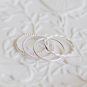May include: Three silver rings with a twisted design, stacked on top of each other on a white background.