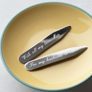 May include: Two silver collar stays with engraved messages. The top stay reads "With all my love, Mia". The bottom stay reads "For my husband to be".
