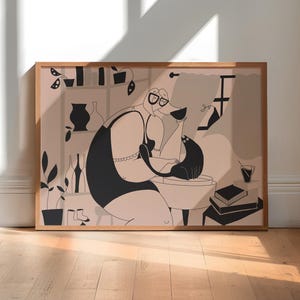 May include: A framed horizontal art print featuring a stylised illustration in black and muted pink. The drawing depicts a figure wearing glasses and a dark tank top, sitting and interacting with a black cat. Shelves with vases, plants, and books are visible.