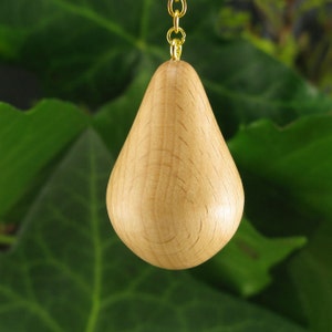 Op de afbeelding: Een houten peer-vormige ornament met een gouden ketting eraan bevestigd. Het ornament is lichtbruin en heeft een gladde, gepolijste afwerking.
