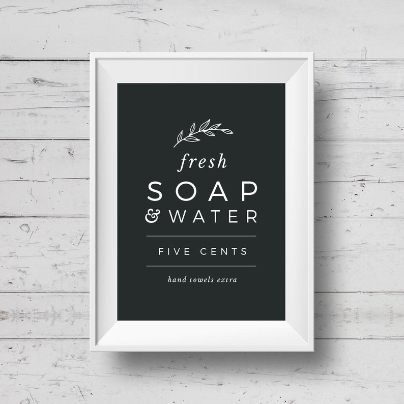 May include: A white framed sign with black background and white text that reads "fresh SOAP & WATER FIVE CENTS hand towels extra". The sign has a small leaf design at the top.