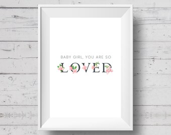 Könnte beinhalten: Ein weiß gerahmter Druck mit dem Text "BABY GIRL, YOU ARE SO LOVED" in schwarzer Schrift. Das Wort "LOVED" ist mit rosa floralen Akzenten verziert. Der Hintergrund ist eine weiße Holzoberfläche.