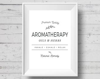May include: A framed white print with the words "AROMATHERAPY OILS & HERBS" in black. The print also includes the phrases "Premium Quality", "Inhale. Exhale. Relax", and "Natural Remedy" in a decorative font. The background is a white wood grain.