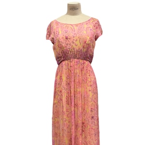 Puede incluir: Un vestido estampado en rosa y amarillo con mangas cortas y cintura ajustada. El vestido está hecho de una tela transparente y tiene un diseño floral.