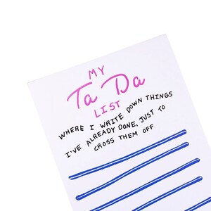 May include: A white notepad with blue lines and the text "MY Ta Da LIST WHERE I WRITE DOWN THINGS I'VE ALREADY DONE, JUST TO CROSS THEM OFF" in black.