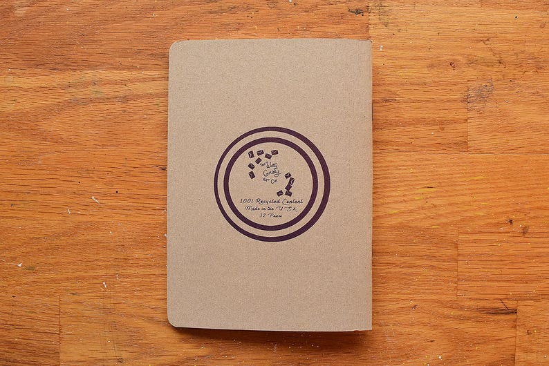 May include: A brown paper notebook with a purple circle logo that says "100% Recycled Content Made in the USA 37 Pages".