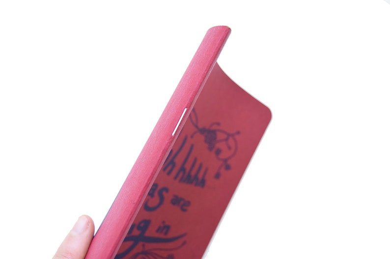 Puede incluir: Un libro de madera rojo con las palabras "Things are going in" y un dise&ntilde;o floral decorativo en azul oscuro. El borde del libro es visible, mostrando una franja de color claro. El libro se sostiene en &aacute;ngulo.