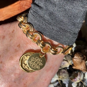 May include: A gold chain bracelet with a large, round charm featuring the initials "L.L." in a cursive font.