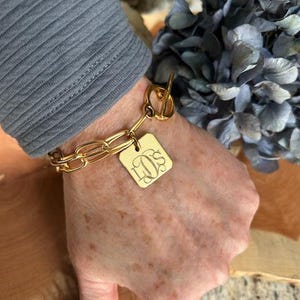 May include: A gold chain bracelet with a square charm engraved with the initials "LOS".