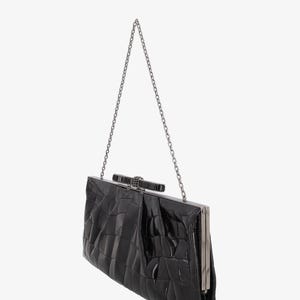 Pode incluir: Clutch preta com al&ccedil;a de corrente prateada. A bolsa retangular tem um padr&atilde;o texturizado semelhante ao de um crocodilo e um fecho prateado. A corrente &eacute; presa na parte superior. Um acess&oacute;rio formal.