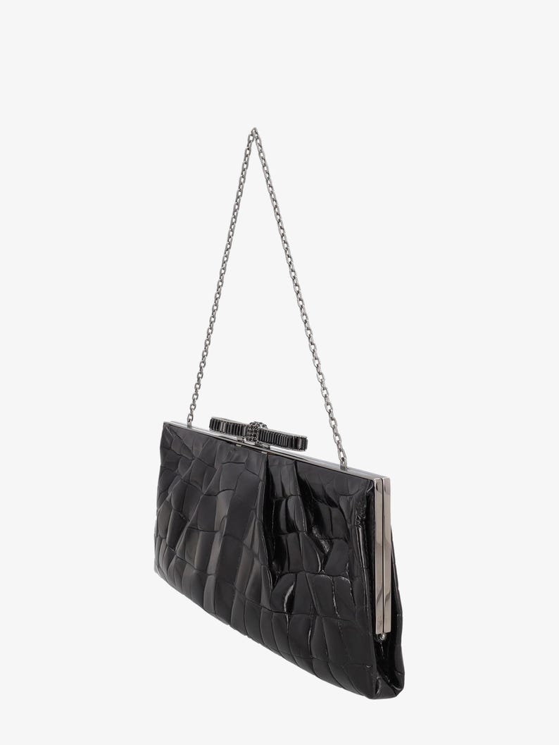 Pode incluir: Clutch preta com al&ccedil;a de corrente prateada. A bolsa retangular tem um padr&atilde;o texturizado semelhante ao de um crocodilo e um fecho prateado. A corrente &eacute; presa na parte superior. Um acess&oacute;rio formal.