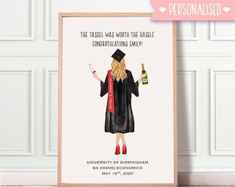 May include: A framed graduation print featuring a cartoon illustration of a graduate in a black gown and cap, holding a diploma and champagne. The print includes the text "The tassel was worth the hassle, Congratulations Emily!" and "Class of 2020".
